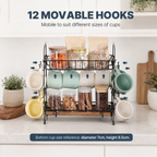 A black metal 12-moveable mug and cup holder rack with a wooden shelf base, shown on a kitchen counter with mugs, jars, and text overlays describing its features. 2-Tier Coffee Bar Organizer with Mug Hooks. Vitly Hub