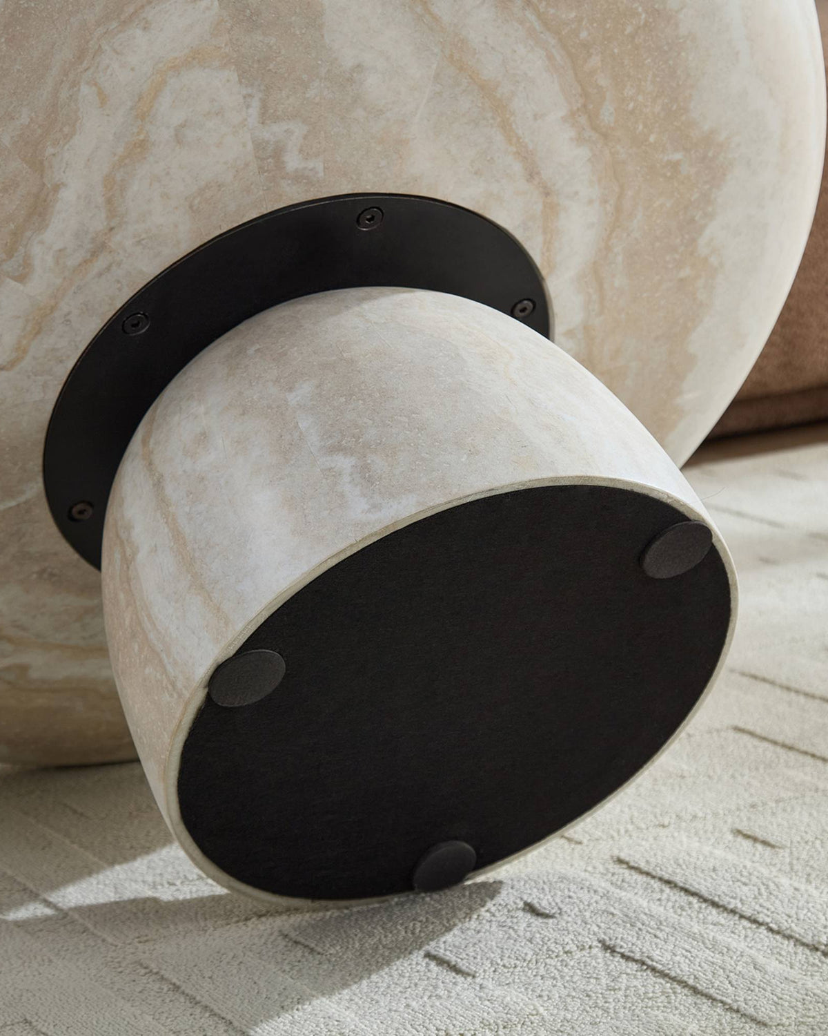 Decorative cylindrical object with marble-like finish and black accents on a textured surface.
