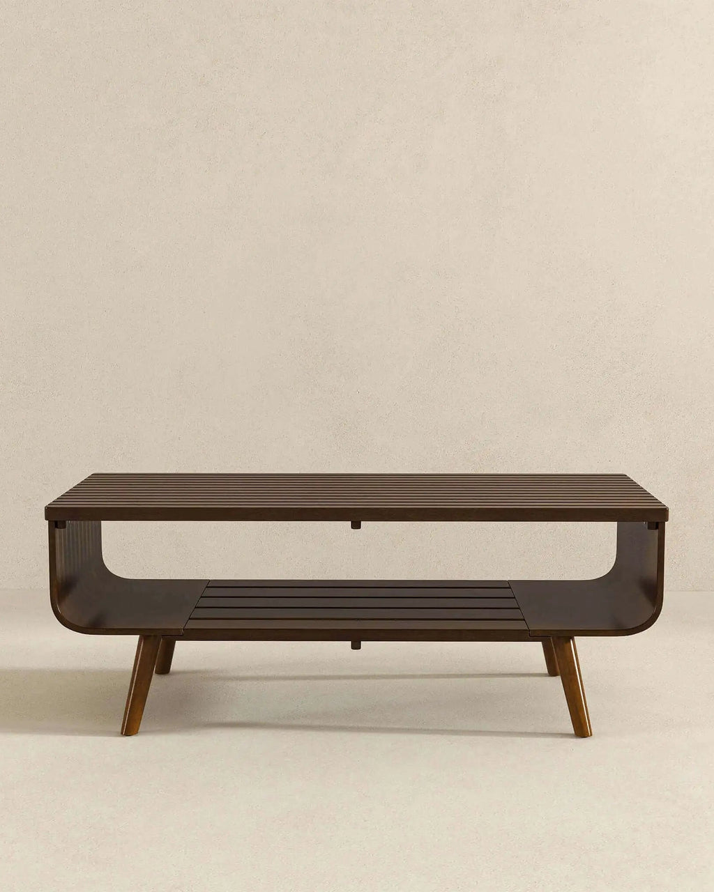 A modern rectangular coffee table with a dark brown wood finish, featuring a lower slatted shelf and tapered legs, set against a neutral beige background.
