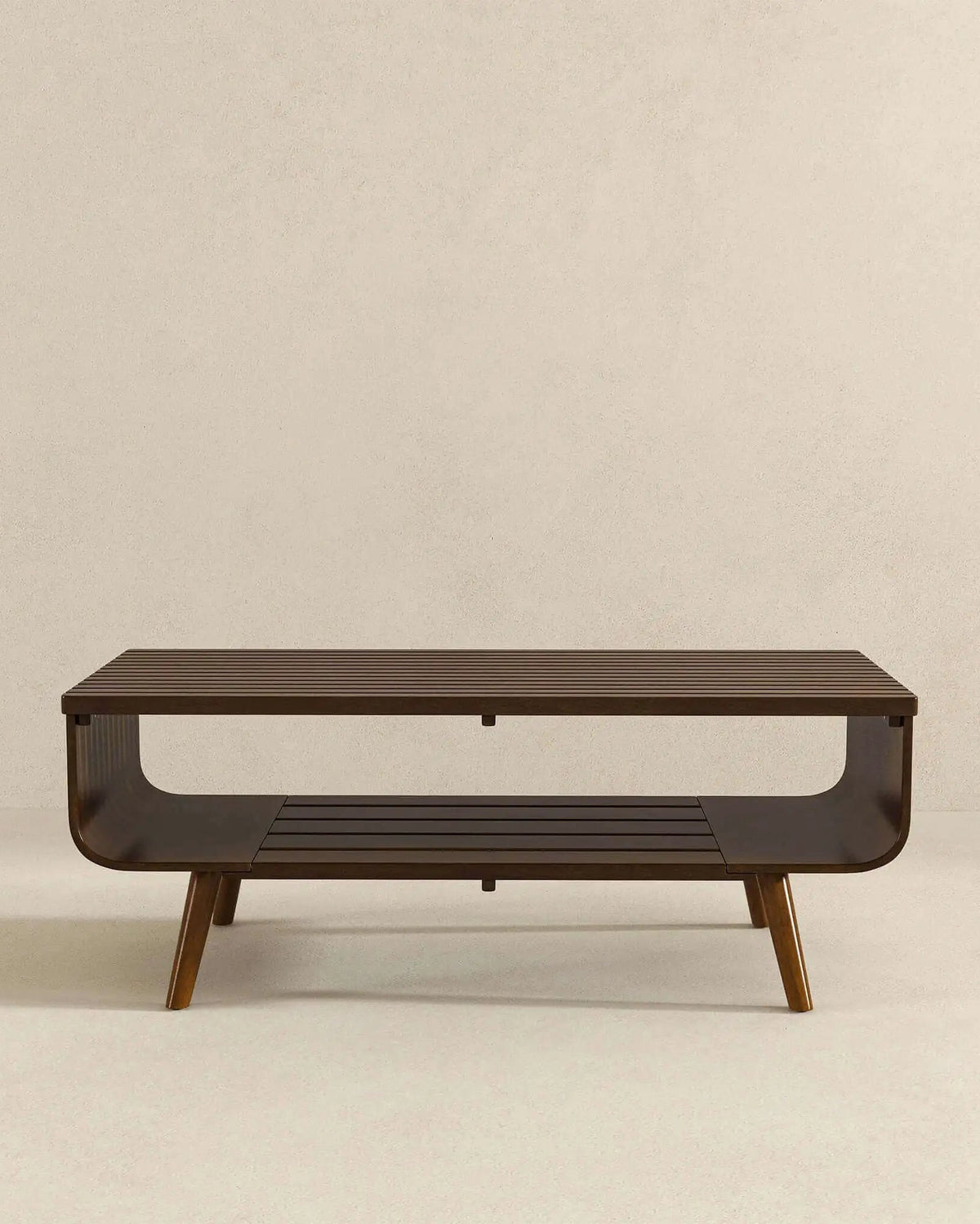 A modern rectangular coffee table with a dark brown wood finish, featuring a lower slatted shelf and tapered legs, set against a neutral beige background.