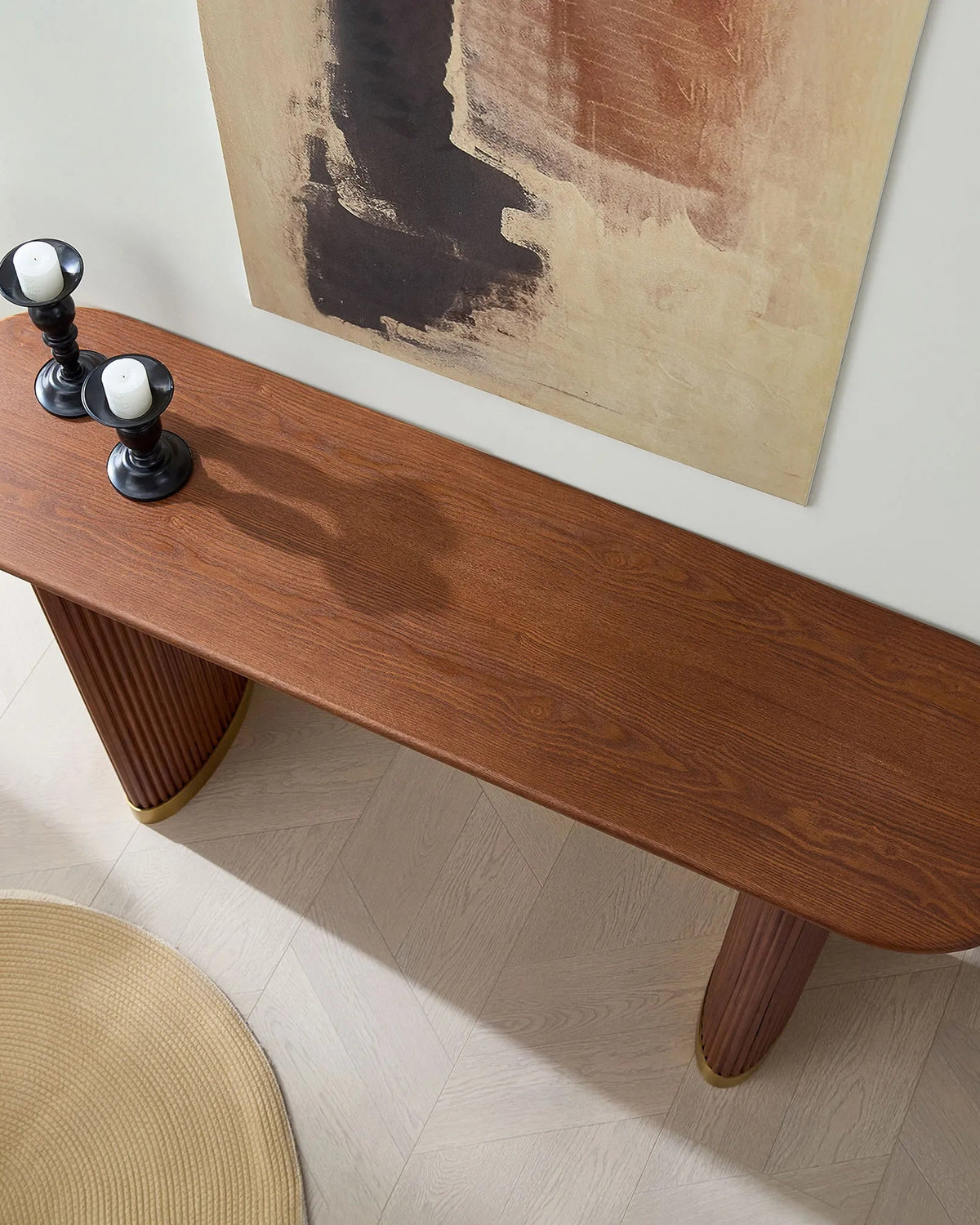 Wooden console table with three cylindrical knobs against a wall with abstract art.