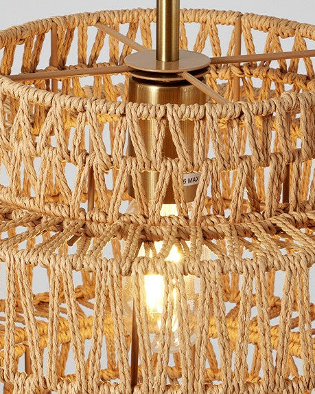 A close-up of a woven natural fiber pendant light fixture with a warm brass metal ceiling mount and visible light bulb.