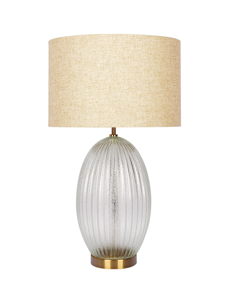 Table lamp with a textured glass base and beige fabric shade on a white background