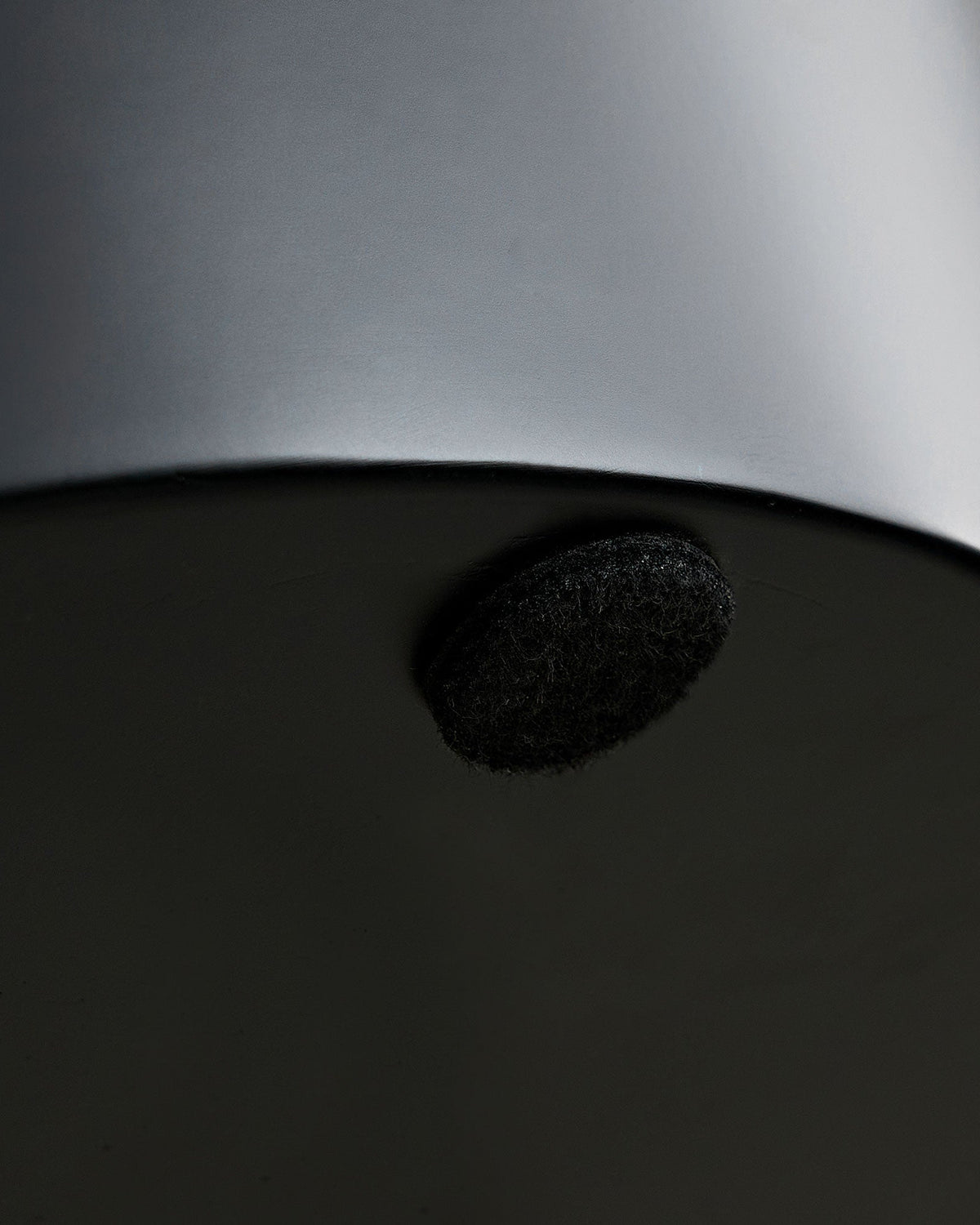 Close-up of a black object on a dark surface with a blurred gray object above.