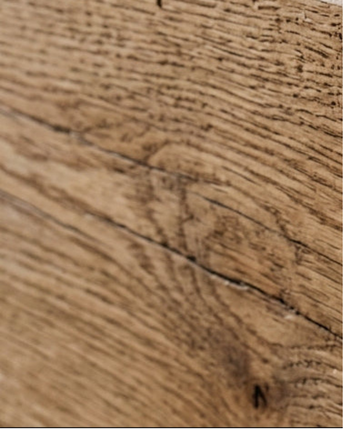 A close-up texture shot of a natural wood surface showing detailed grain patterns and a prominent crack running diagonally across the frame.